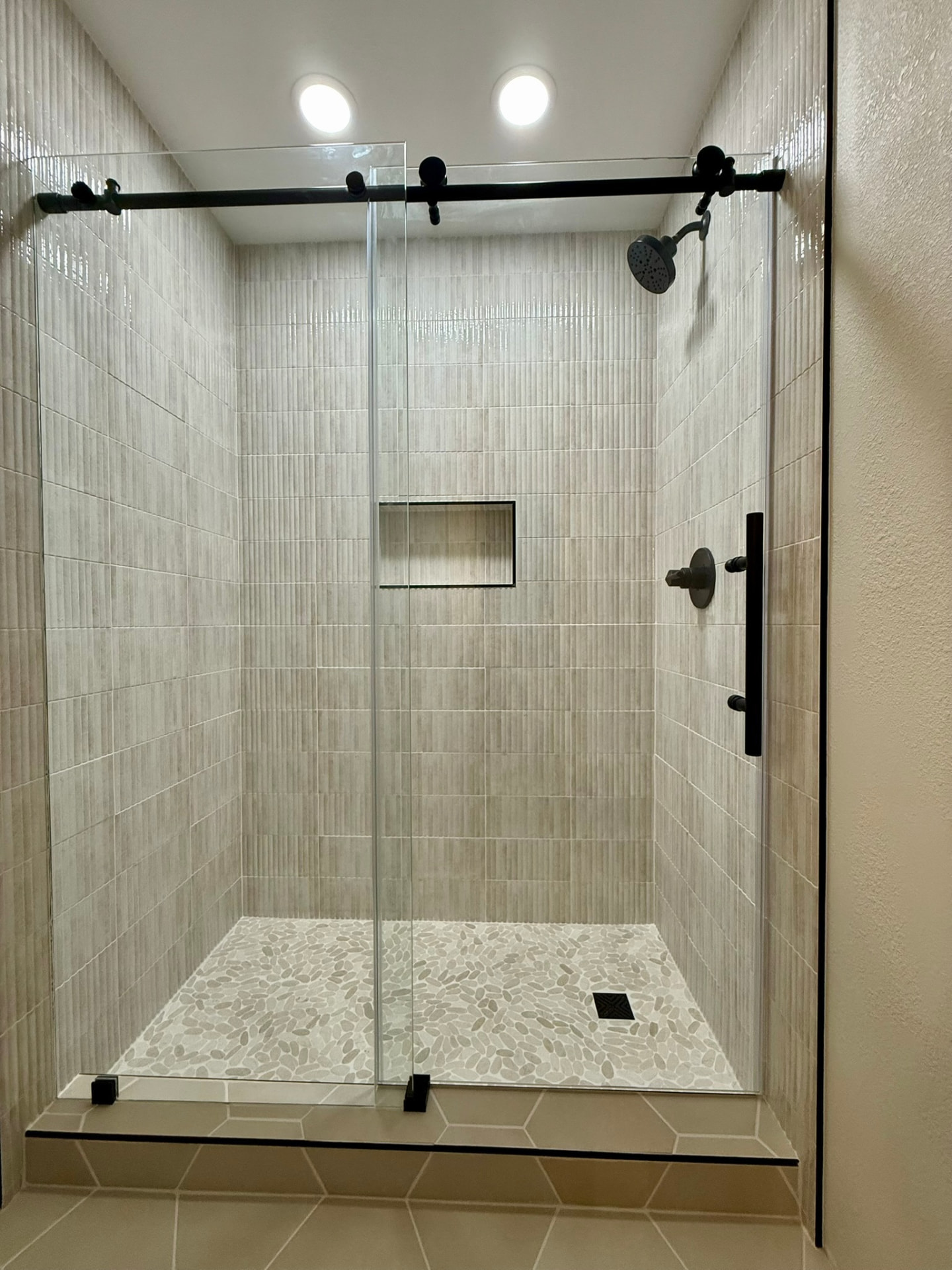 Walk-in shower with vertical stacked tile and pebble floor
